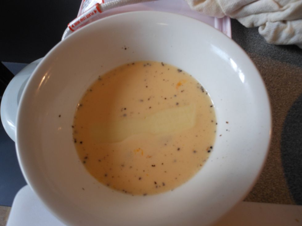 Place one of the cheese sticks in the egg mixture.