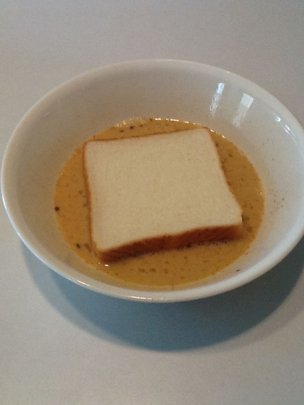 Place one piece of bread in the mixture, just to coat the bottom.