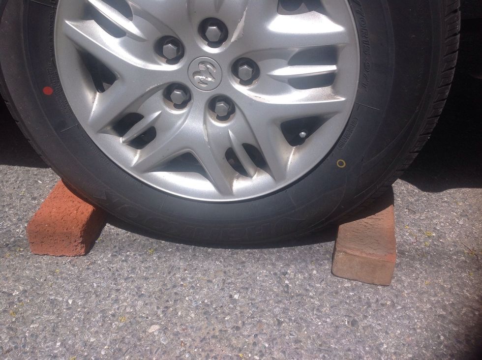 Place pieces of wood/large blocks up tight against the front and the back of the tire that is diagonally across from the one being changed. This will eliminate any possible chances of the car rolling.