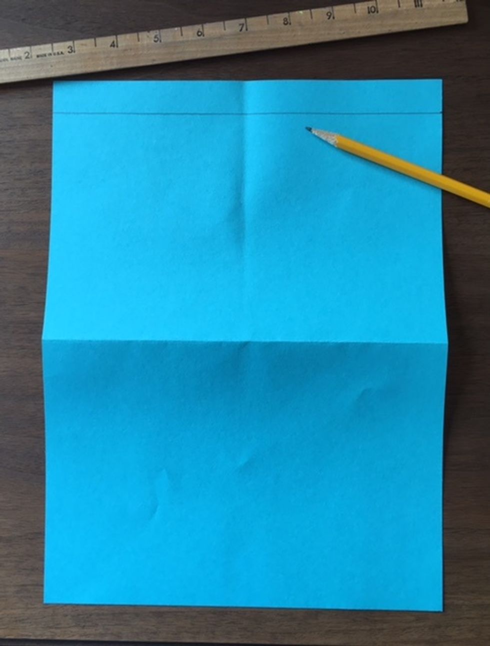 Place ruler along to edge of paper. Hold firmly. Using a pencil, draw a line across the paper, using the bottom edge of ruler as a guide.
