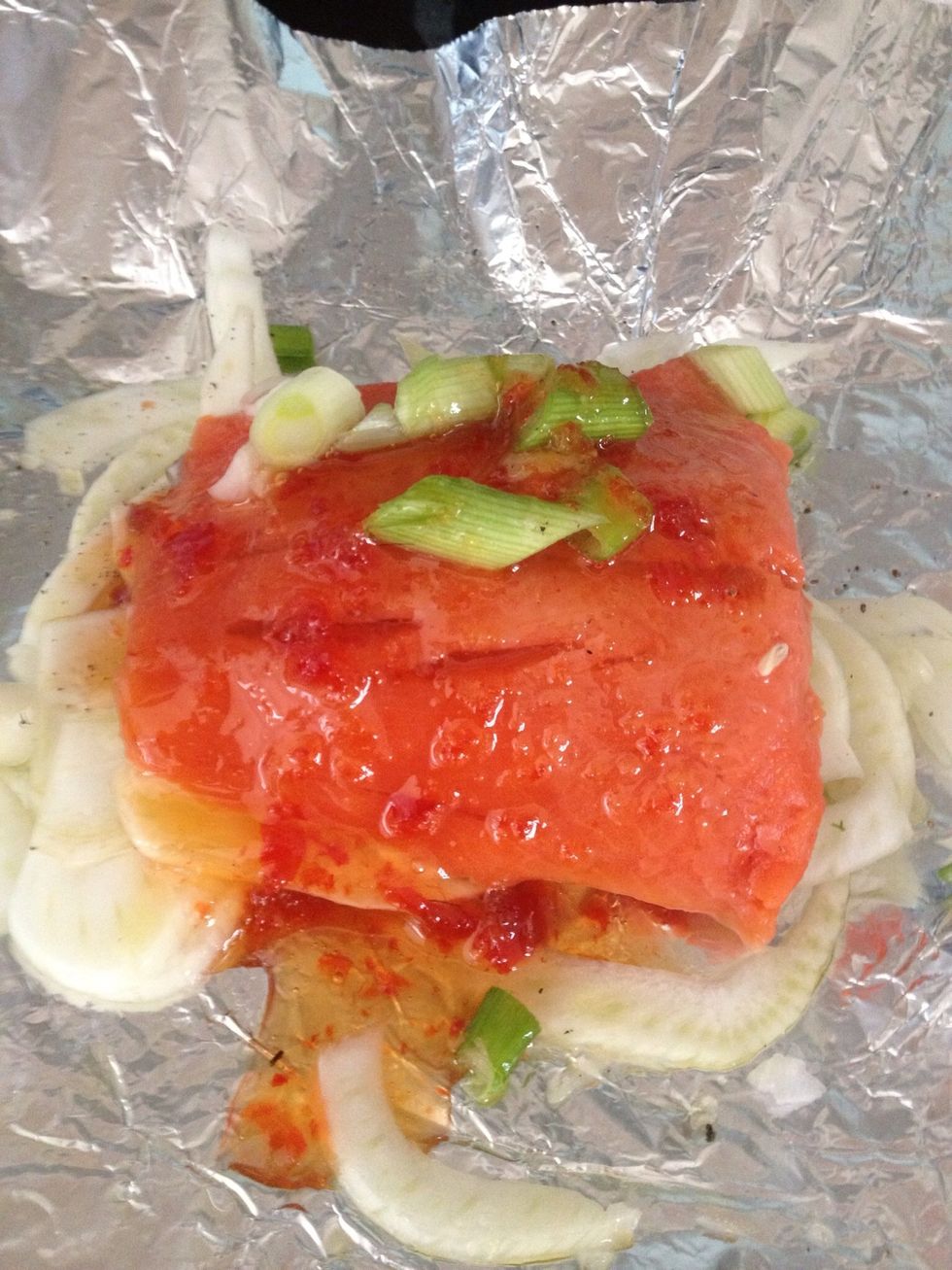 Place salmon fillet on top of the fennel. Squeeze on some lemon. Drizzle on the sesame & teriyaki. Scatter spring onions on top. Pour over the sweet chilli sauce (My favourite is from Riverford farms)