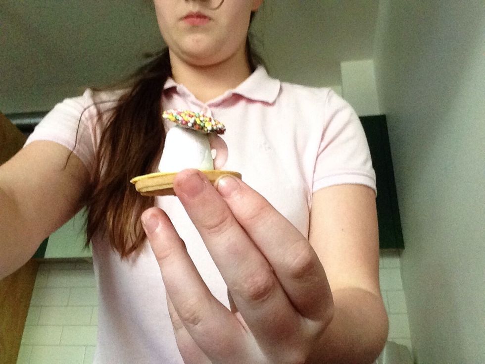 Place some icing on the bottom of the freckle and stick it to the top of the marshmallow. You might need to press them together to make them stick