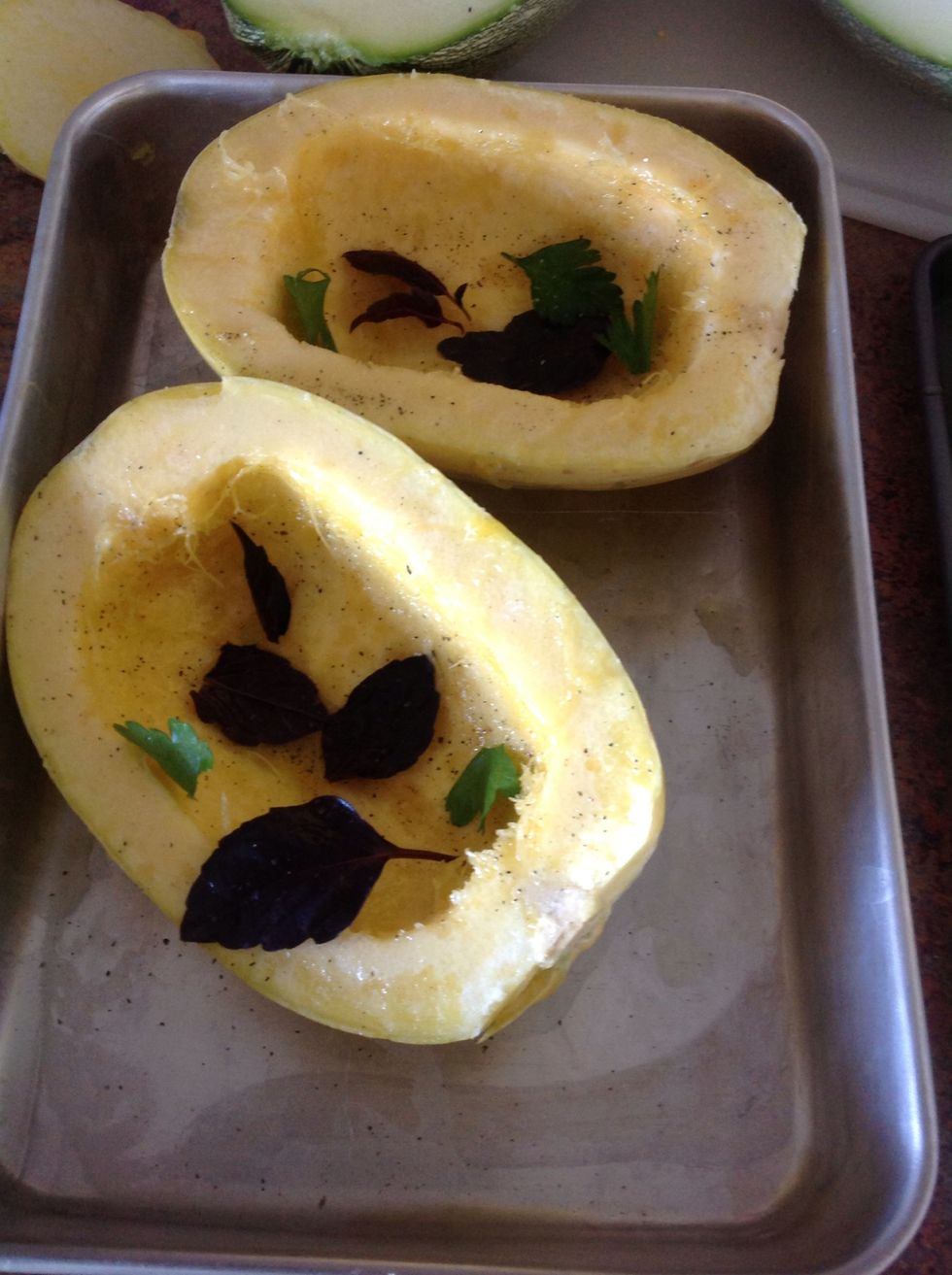 Place squash facing up on baking sheet. Drizzle olive oil on it then lay fresh basil and parsley on the squash.