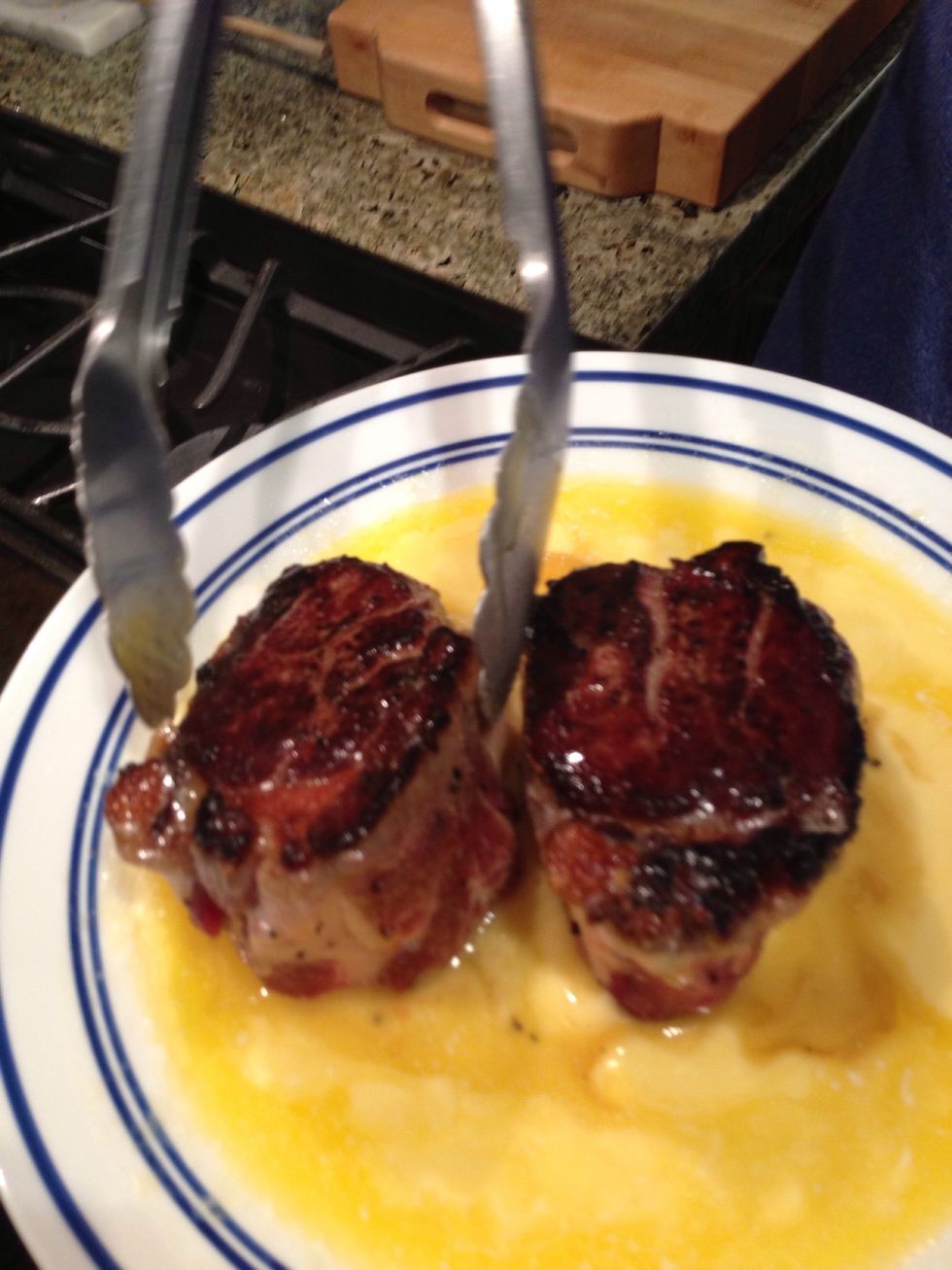 Place steak back in plate of butter, cooked side down. Flip uncooked side down, then place back on cooking surface. If skillet is hot enough, the butter may ignite, which is optimal for searing.