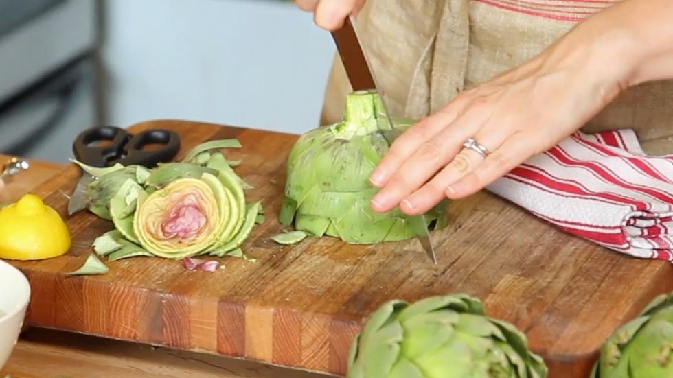 Place the artichoke on your cutting board. Use a chef\u2019s knife to slice vertically through the middle of the stem and the rest of the artichoke.