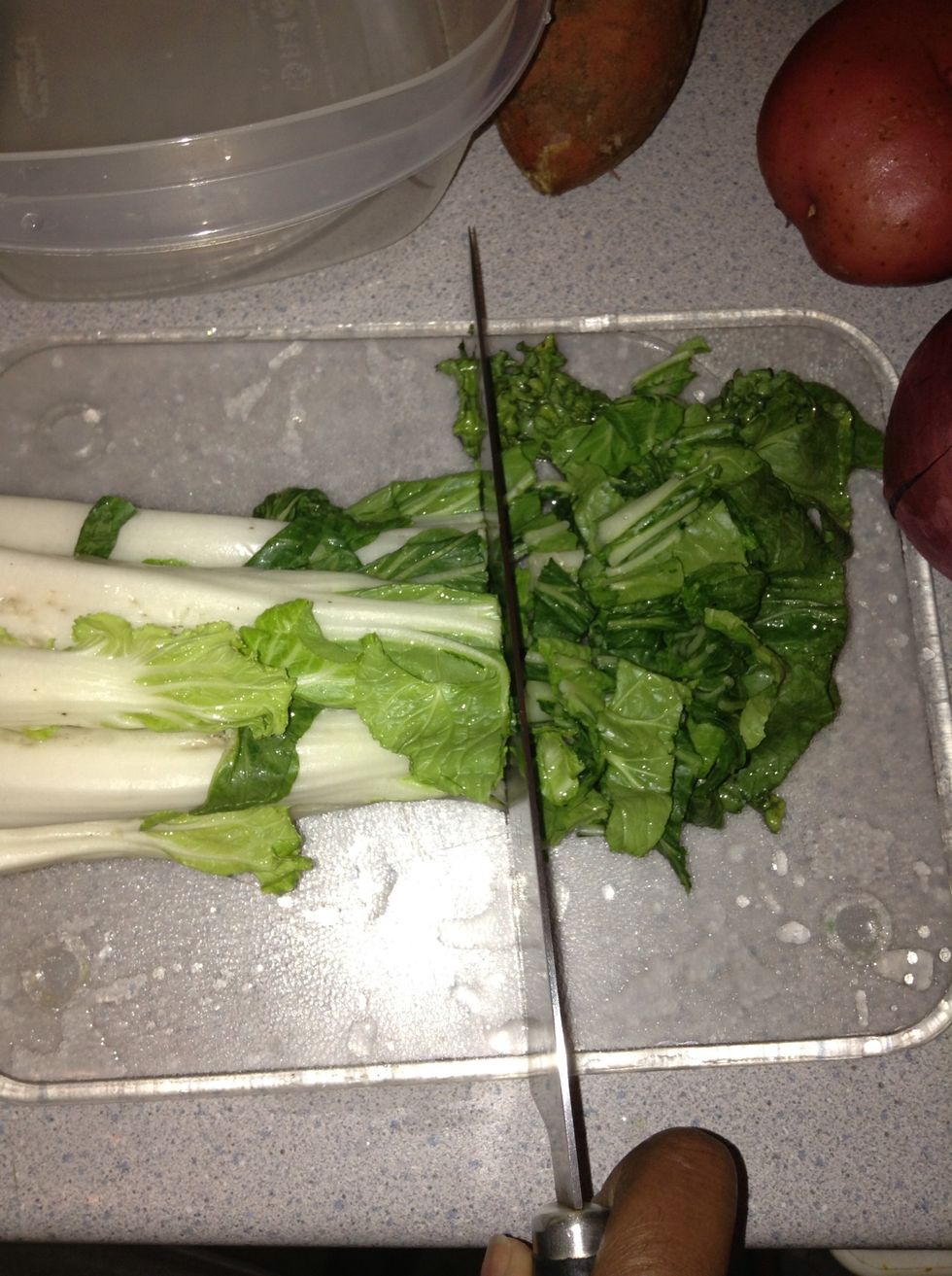 Place the bundle of washed Bok choy on the cutting board and chop from leaves to stalks