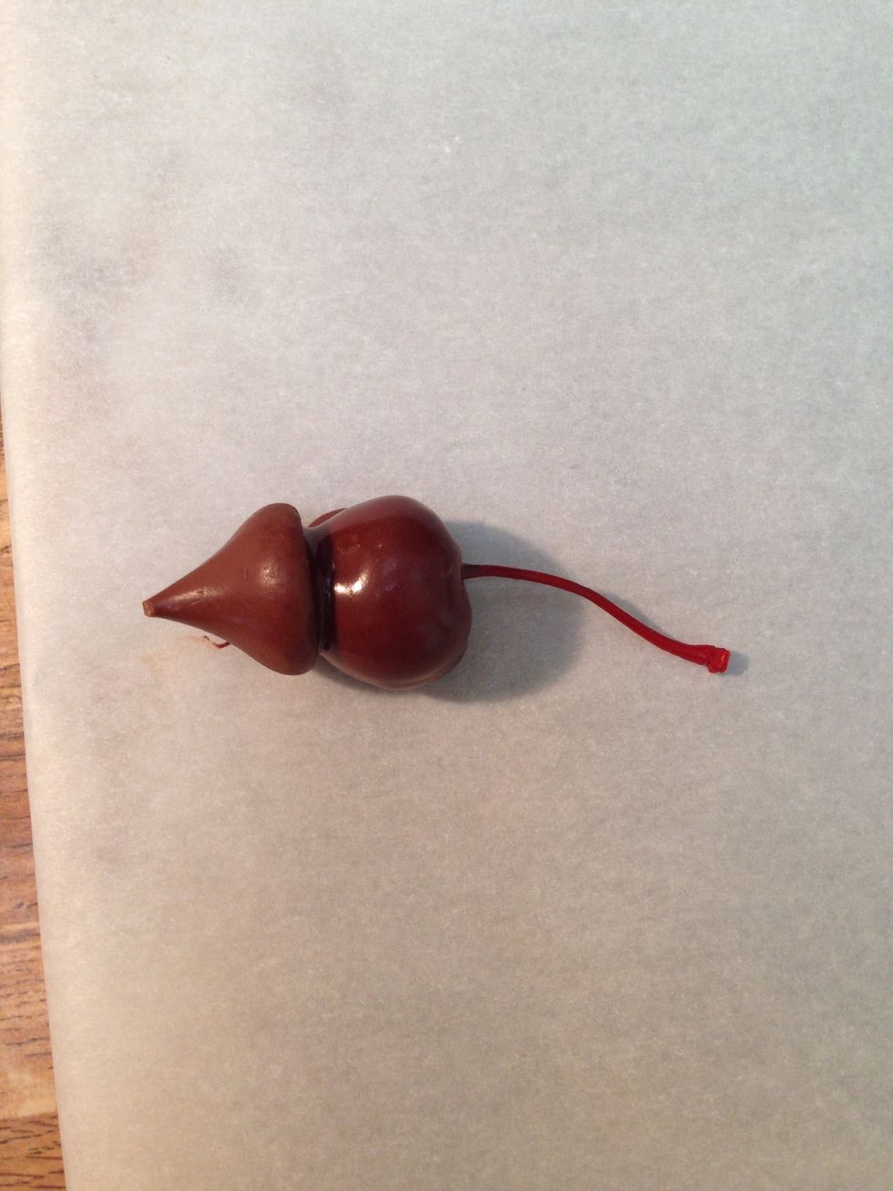 Place the cherry on your cookie sheet and immediately push the flat end of the kiss on the cherry.
