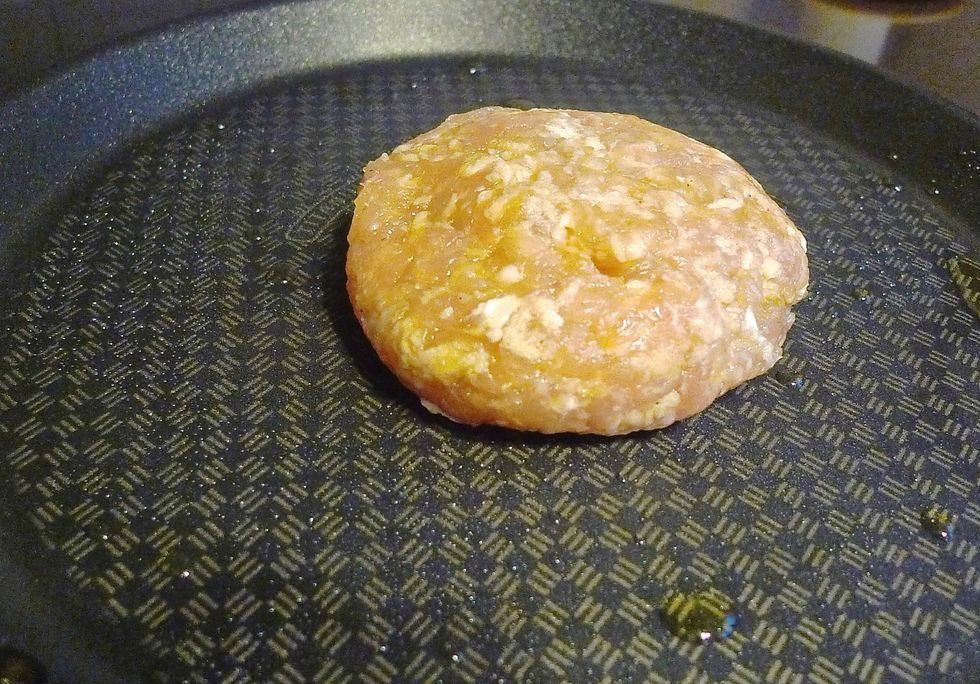 Place the chicken patty on the hot skillet.