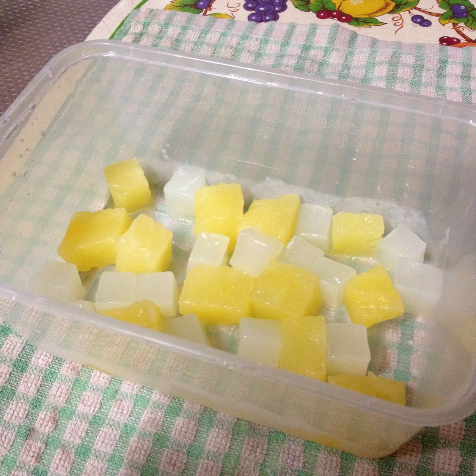 Place the cubes of pineapples and nata de coco into a container (the container or mould that will hold the jelly).
