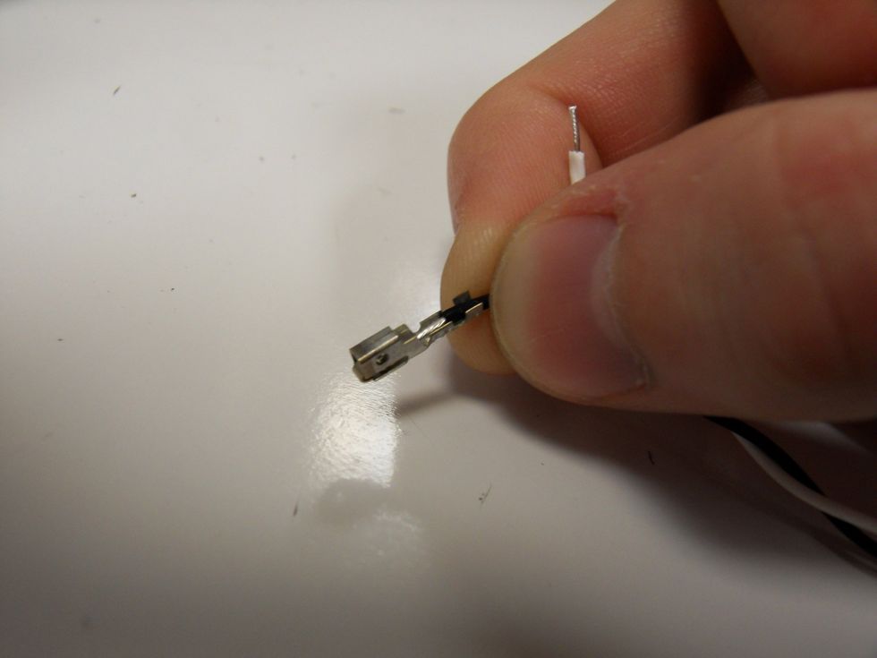 Place the end into the metal socket positioning the wire such that the exposed wire is settled between one set of tabs and the insulation is settled between the other.