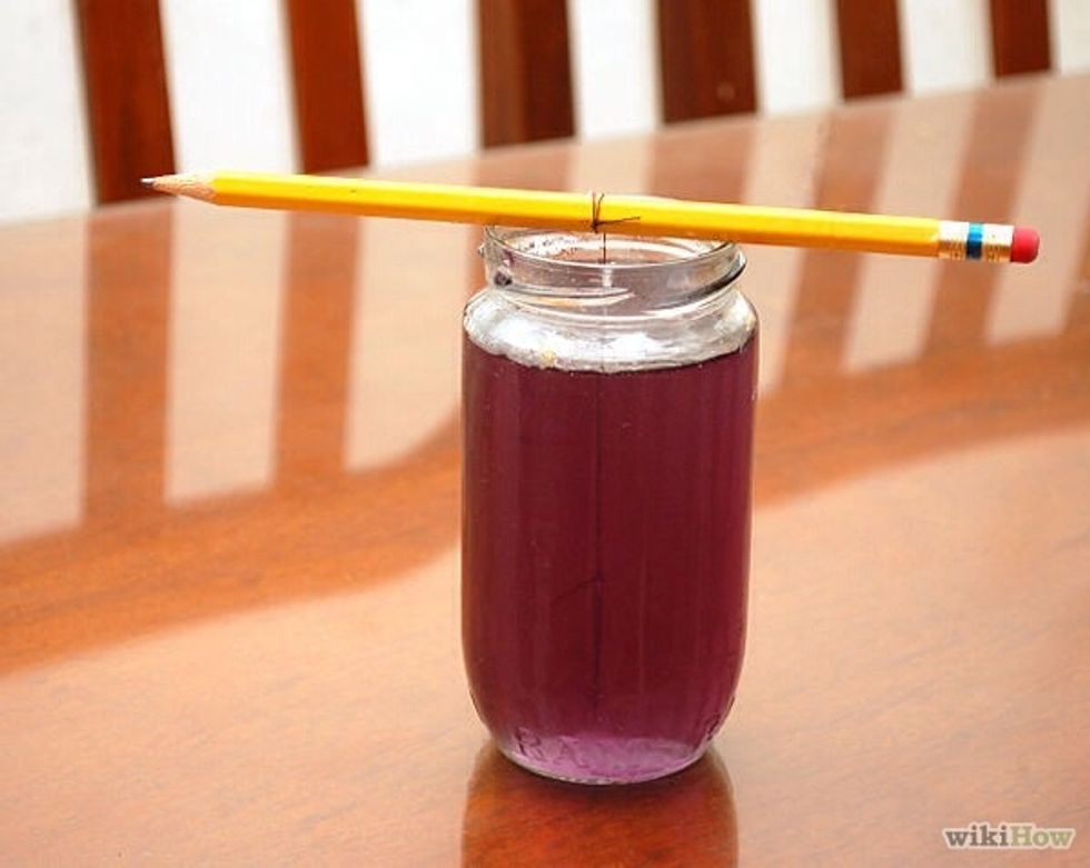 Place the glass somewhere where it can sit for a while undisturbed (but do not refrigerate it). After a day or so, you should start to see crystal growth forming on the string.