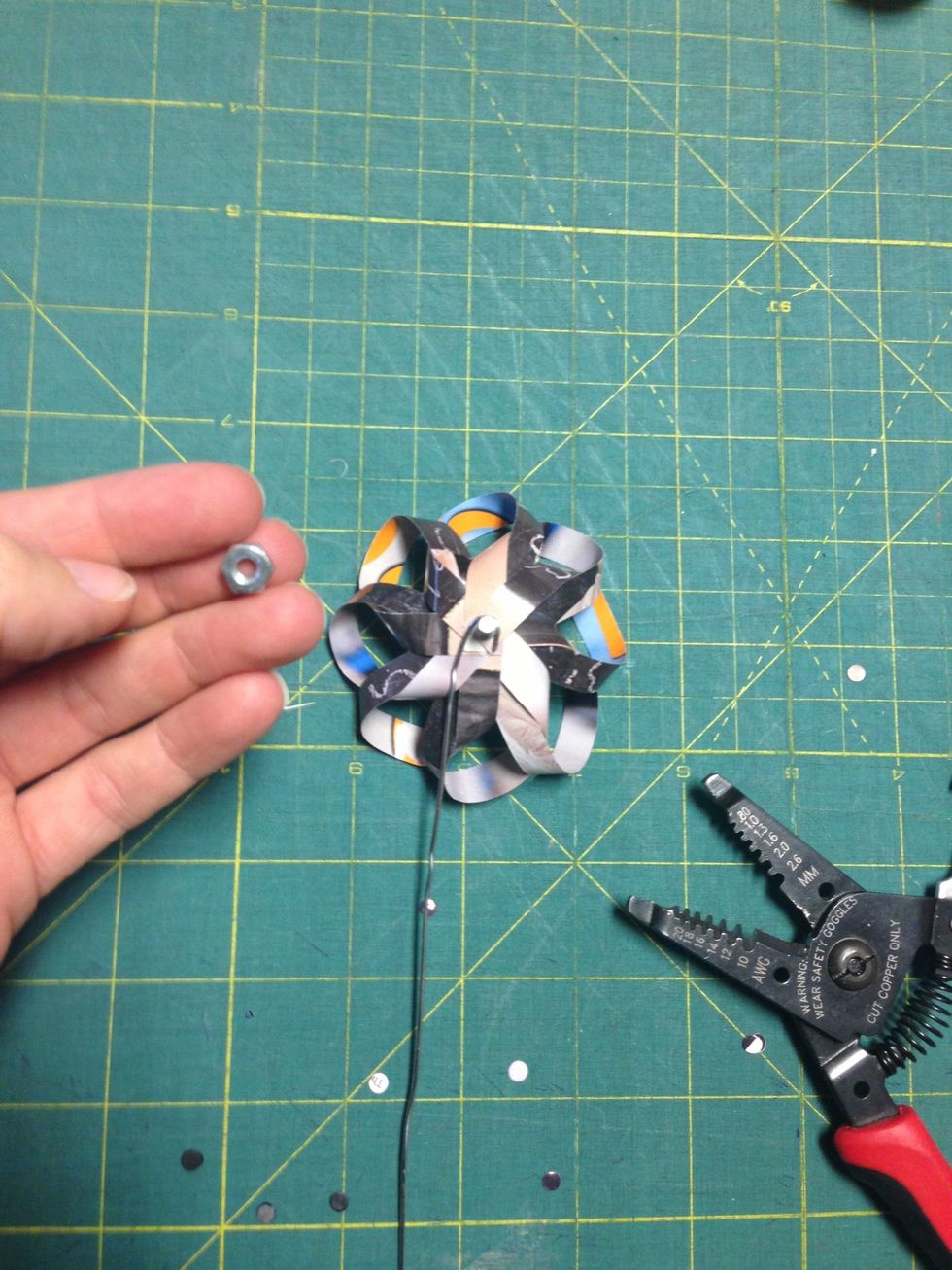 Place the hook of the paper clip around the bolt and screw on the nut to hold everything in place. Be careful not to excessively twist the strips of material under the nut.