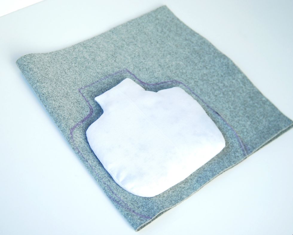 Place the inner stuffed with rice pillow on the fabric folded in half, draw the outline, leaving a border of about 1 cm for sewing