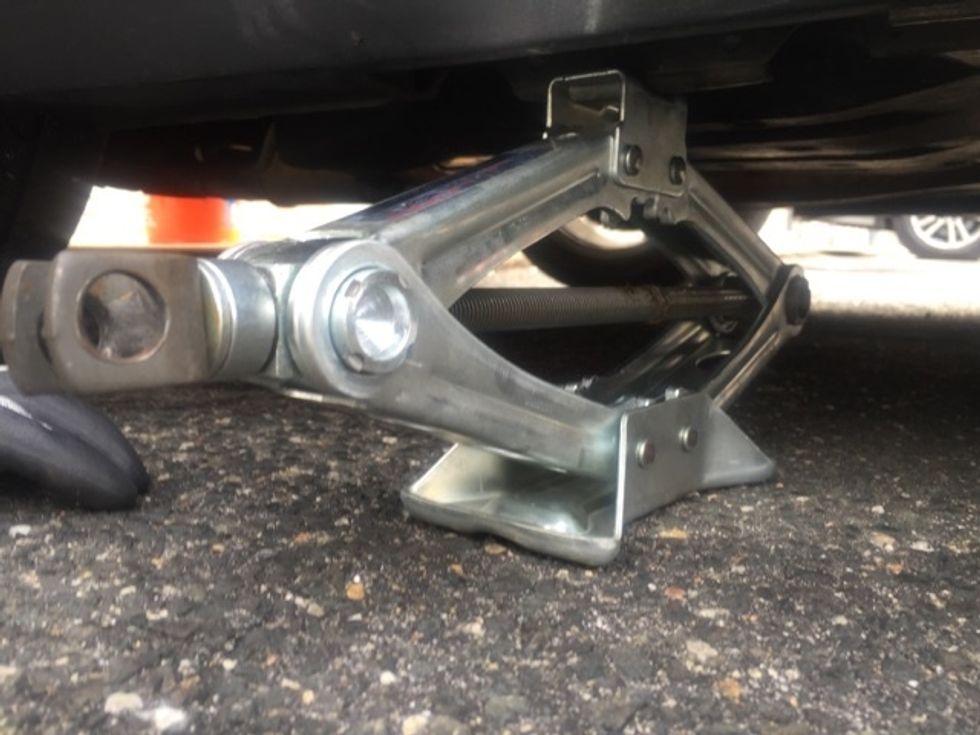 Place the jack underneath the previously indicated part of undercarriage. Use your hand to lift jack until it is flush with the vehicle.