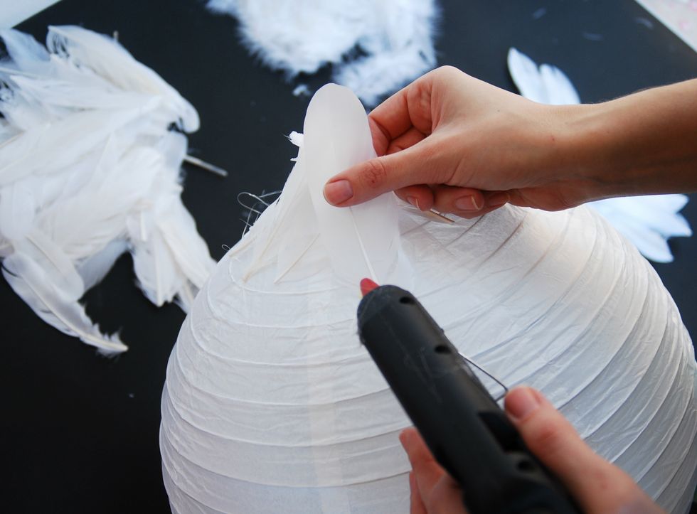 Place the lantern as the bottom part facing up and glue the middle size feathers around the bottom of the lantern. Continue the same row by row, as the big feather are in the central part of lantern.
