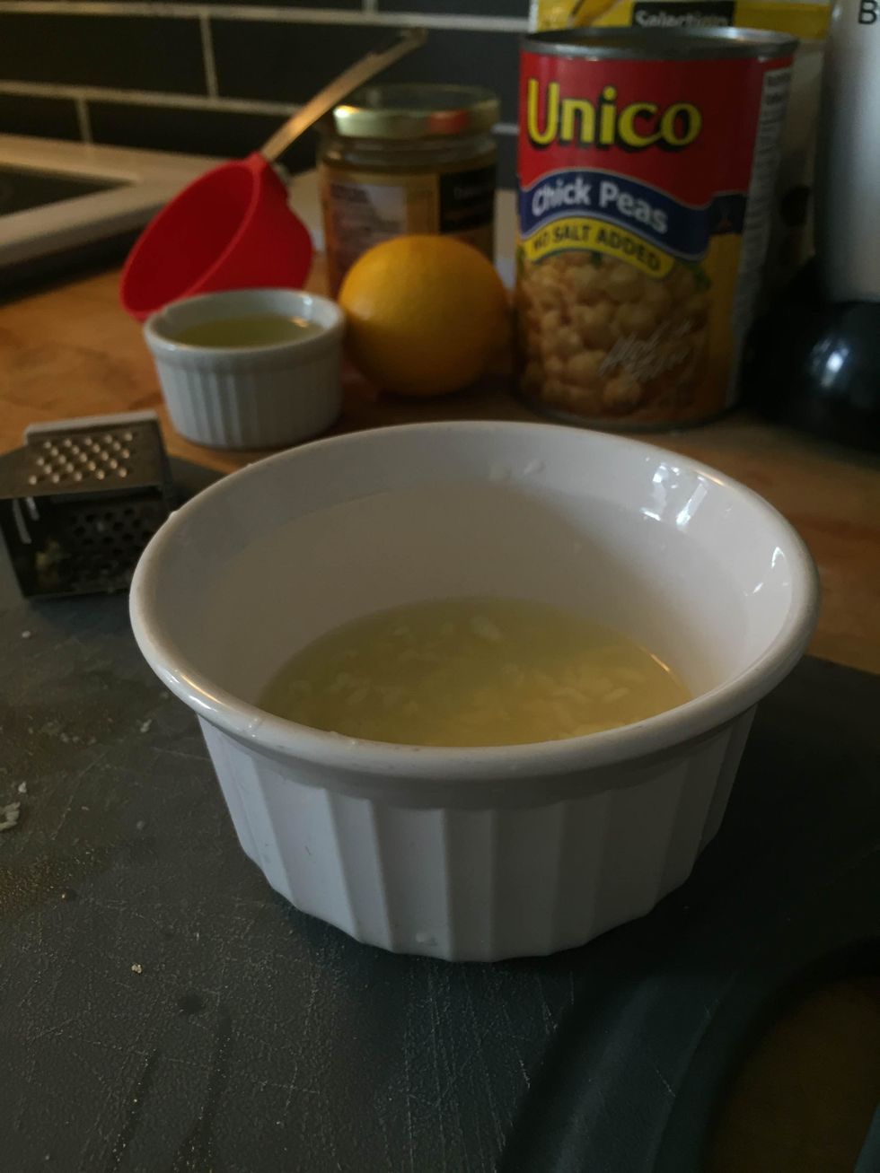 Place the minced garlic in the lemon juice and let sit for 10-15 minutes. Afterwards, add \u00bc cup of water to the lemon and garlic mixture.