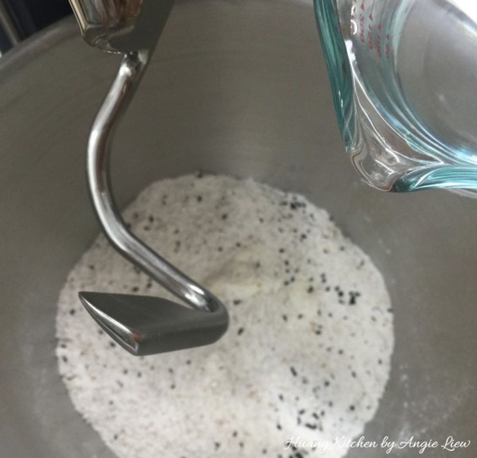 Place the mixing bowl onto a stand mixer with a dough hook affixed. Slowly add in the water.