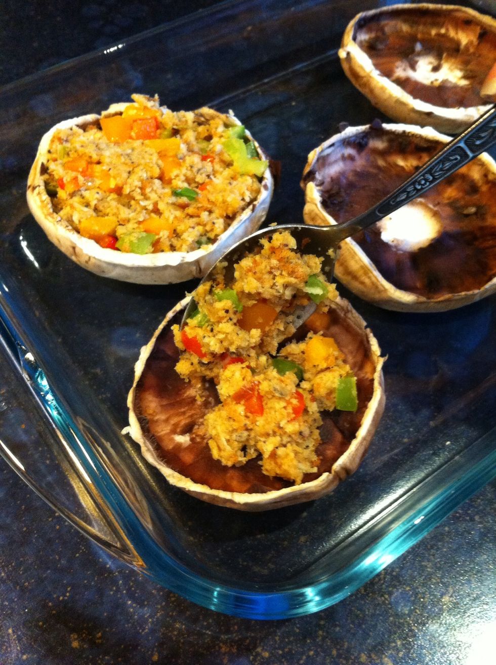 Place the mushrooms into a baking tray and add 2 table spoons of the breadcrumb stuffing into each mushroom. Pat with a spoon to flatten the mixture so it does not fall out while in the oven