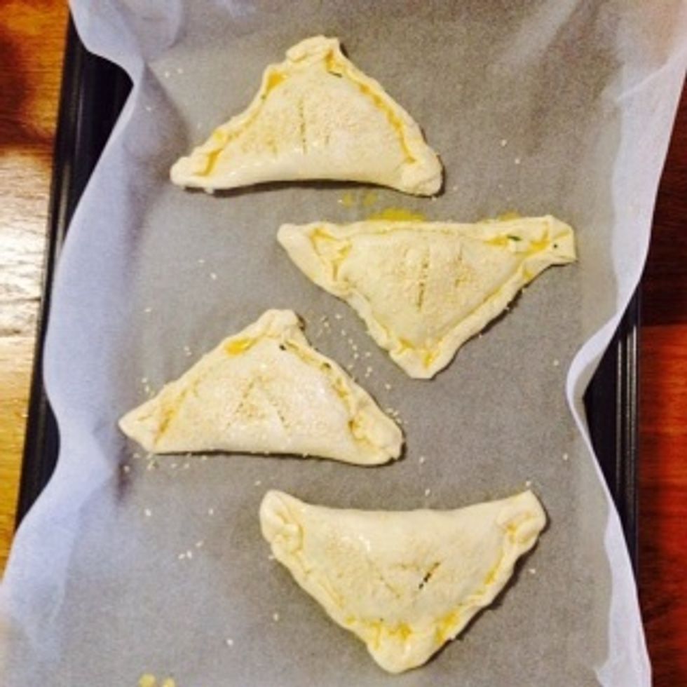 Place the pastries in the baking trays. Brush the tops of the Borekas with egg, and sprinkle with sesame seeds.
