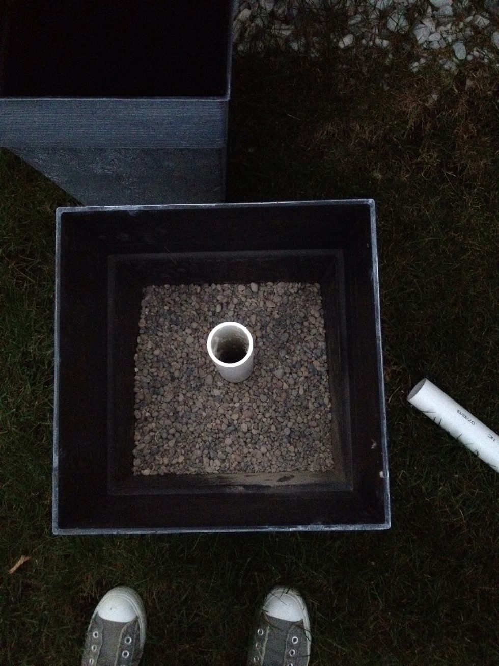 Place the PVC pipe in the center of each planter. Fill the planter with 2 bags of pebbles.