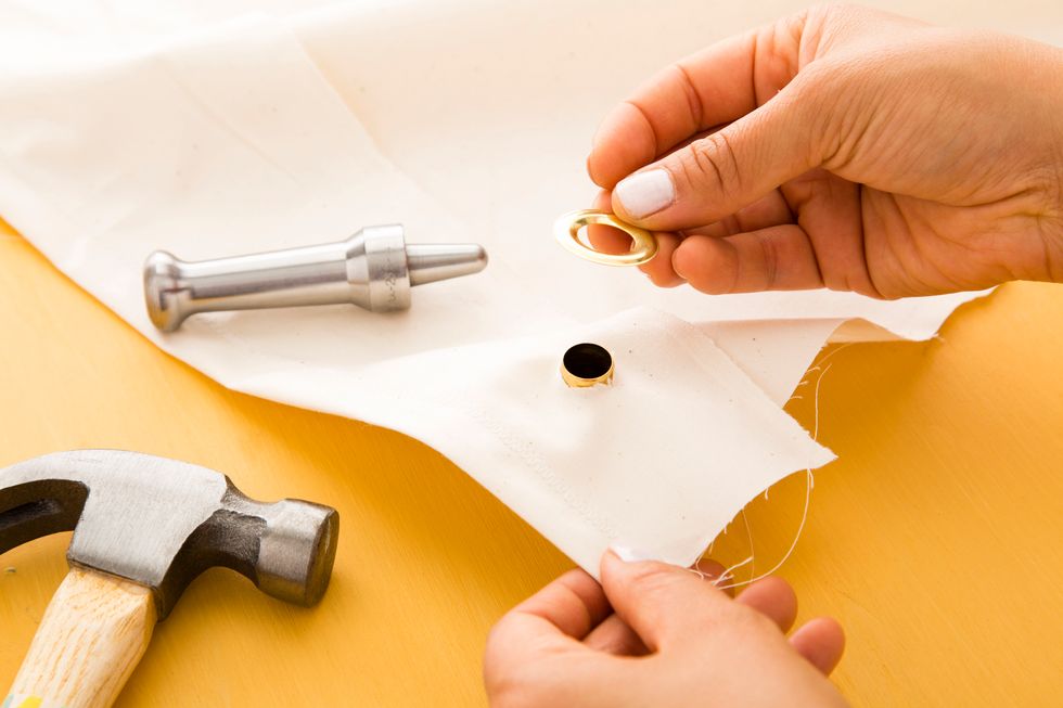 Place the raised grommet piece on the grommet tool, layer your fabric on top and put the other piece on top of the fabric.