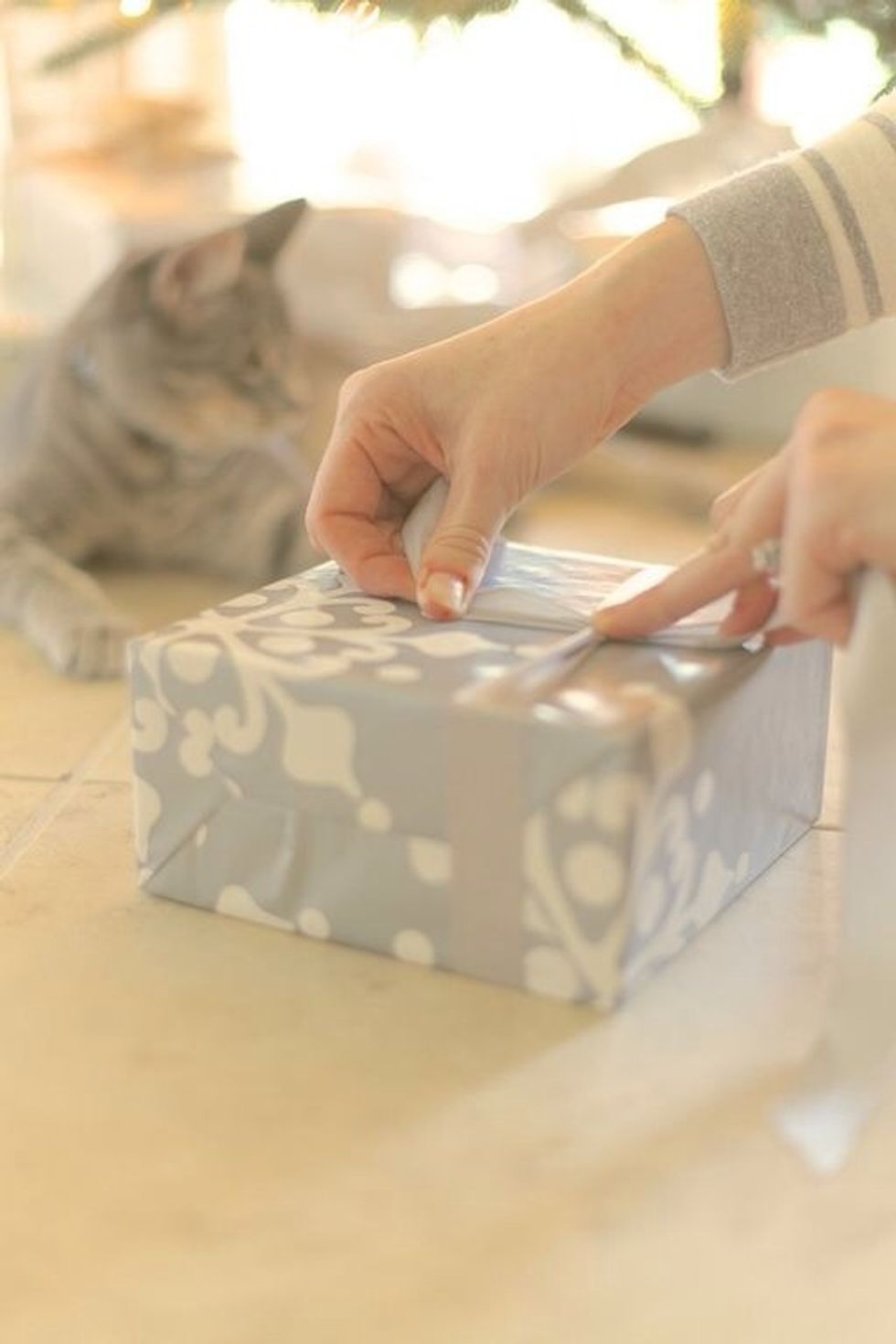 Place the ribbon under the gift and make sure each side is equal in length. I like the satin side of the ribbon out. Tie a knot in the center as tight as you can and hold the knot in place.