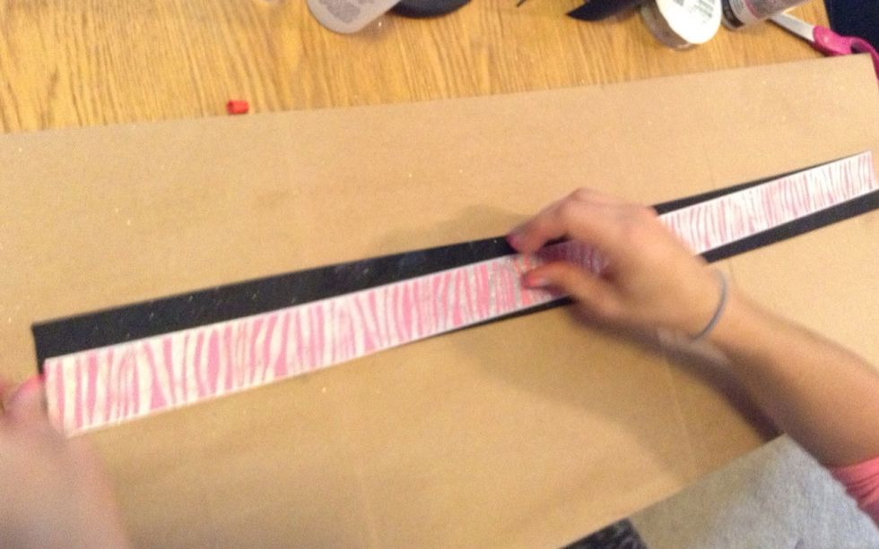 Place the smaller ribbon on top of the larger one with the end of the small ribbon at the bottom left corner and take it diagonal to the top of the right corner.