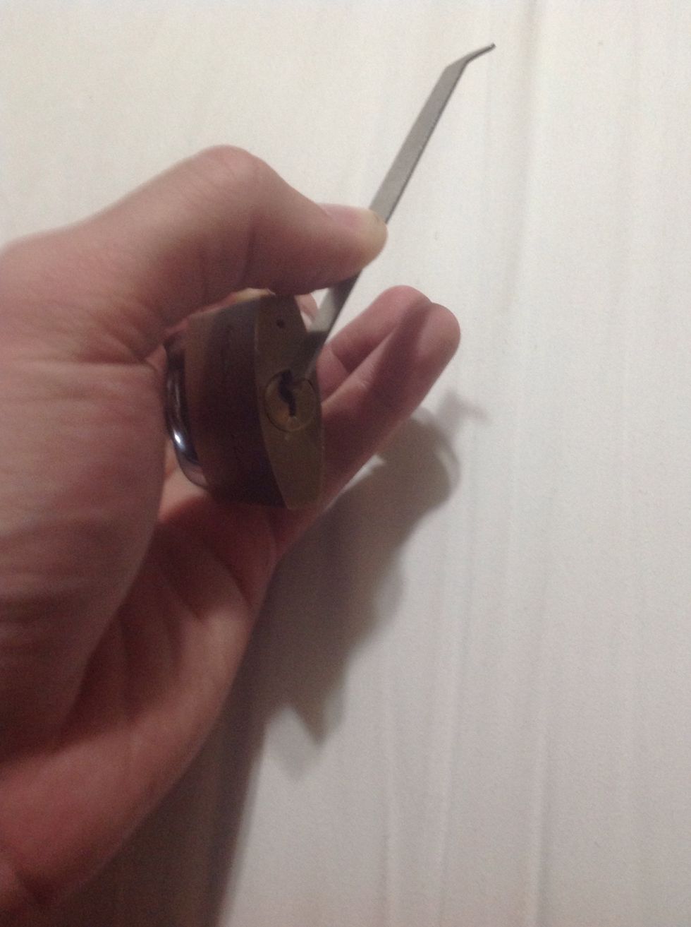 Place the tension wrench into the keyhole opposite of the pins. In this case, the top. And apply pressure on the wrench in whichever way the lock turns.