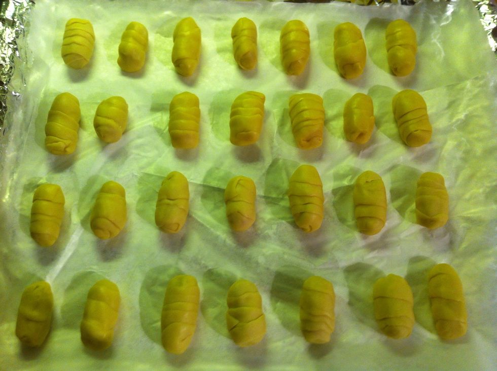 Place the "teque\u00f1os" on a baking tray. If you want you can use a pastry brush to sprinkle some milk on the surface of each teque\u00f1o, in order to make them more golden brown