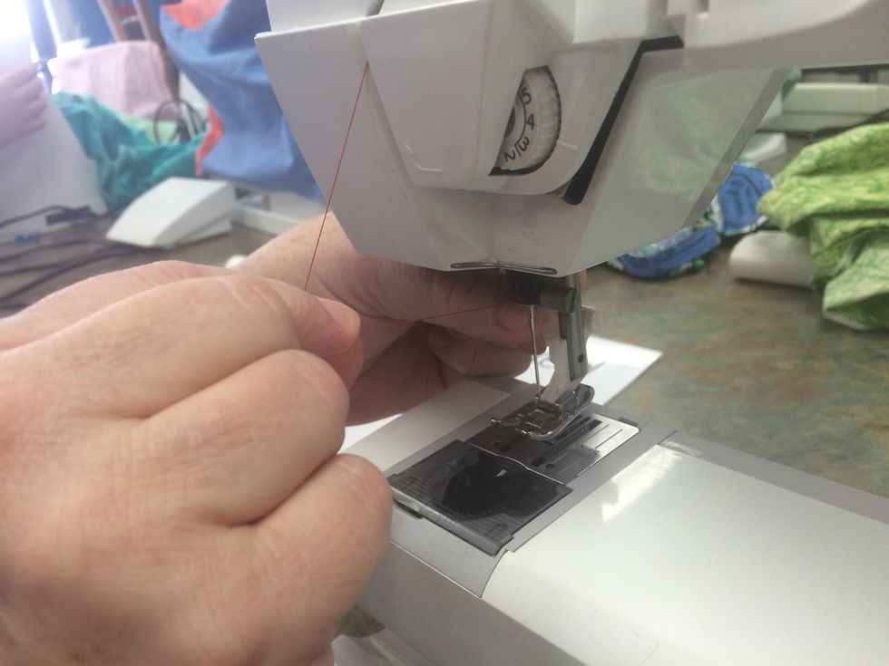 Place the thread between your hands and make sure it is tight. Guide the thread through that last thread guide coming in on the left side.