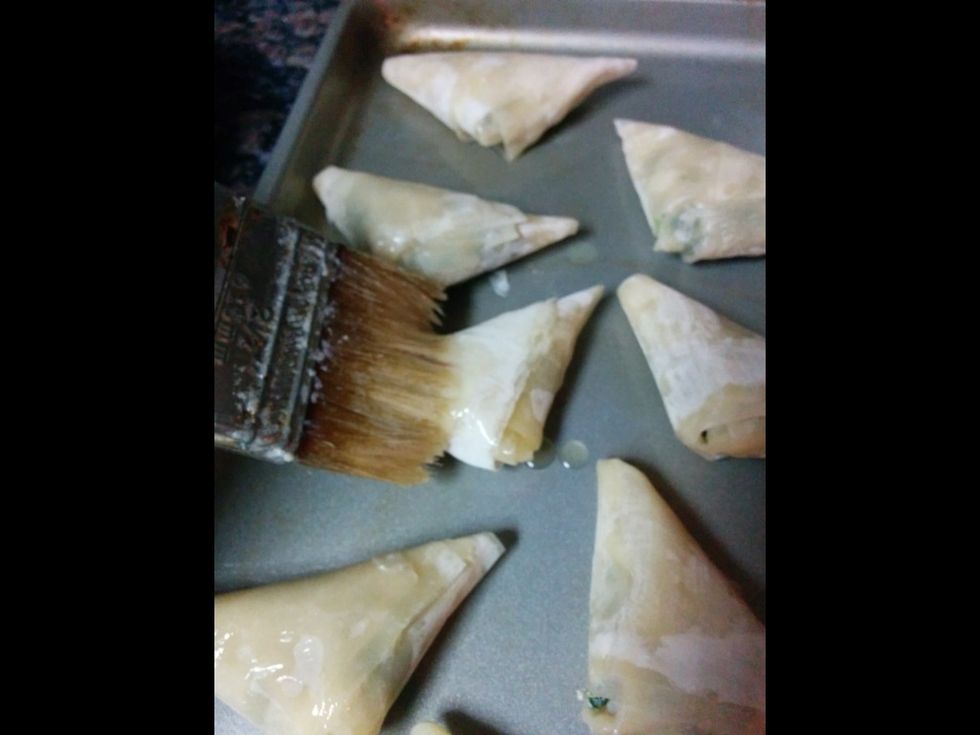 Place the triangles on a cookie sheet and brush with butter