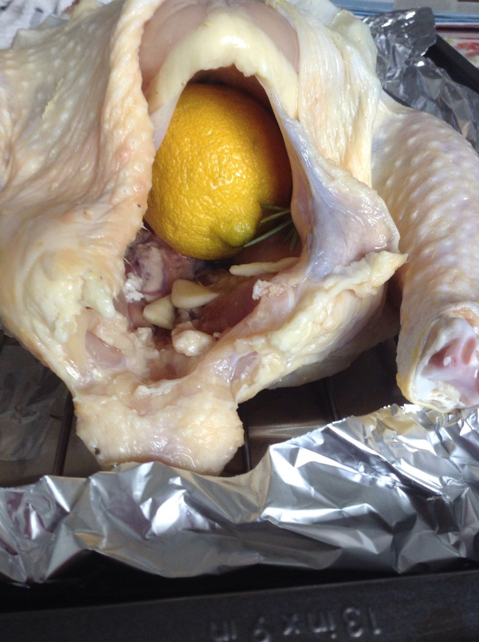 Place the whole lemon along with some more slices of garlic and sprigs of rosemary in the cavity of the chicken.