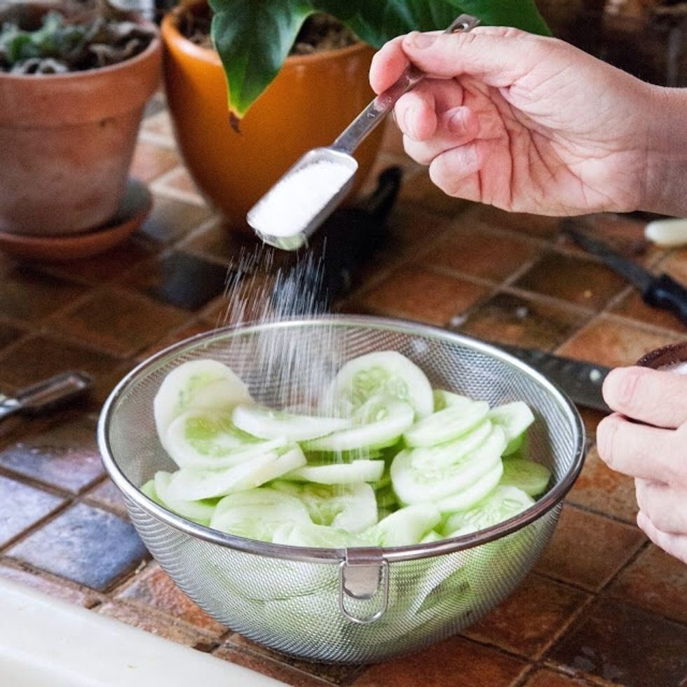 Place them in a colander and sprinkle them with about 3 Tbs of kosher salt. Massage the salt into the cucumbers and set them aside to drain for about 30 minutes.