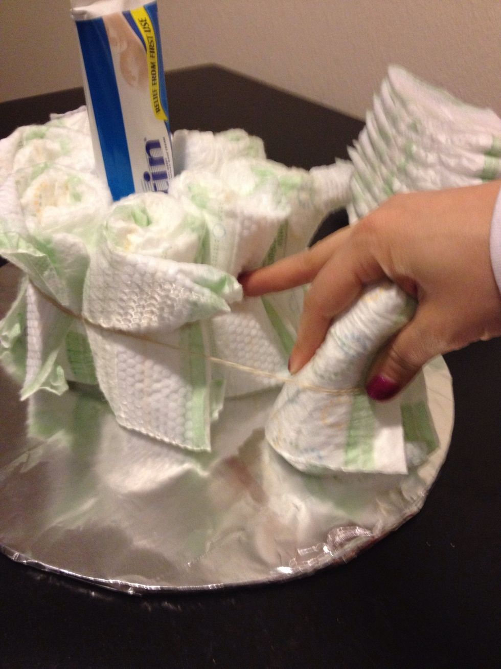 Place tube in the middle of the cake form and surround with a layer of diapers with a larger rubber band keeping it together.