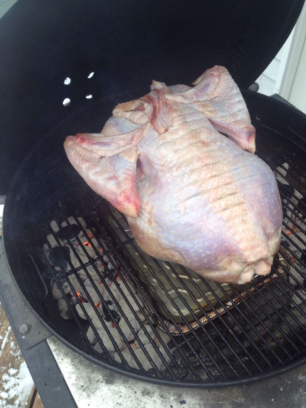 Place turkey breast side down on grill over pan, add about 1/4 cup of drained wood chips on each bank of hot coals cover with lid adjust top vent to 1/4 open, bottom vent 1/2 open.