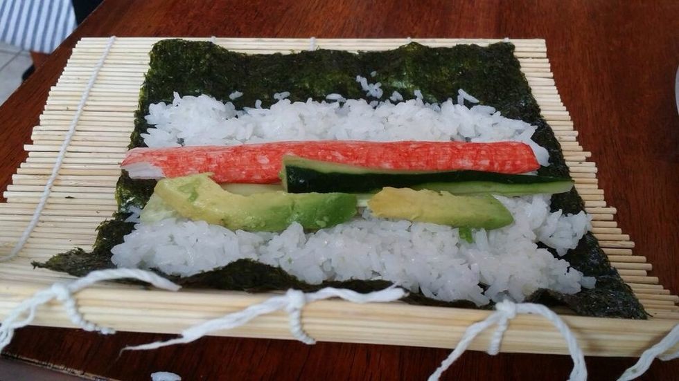 Place two avocado slices parallel to the cucumber slices on the side that is facing you. The cucumber slices should be in the middle of the avocado slices and the imitation crab leg.