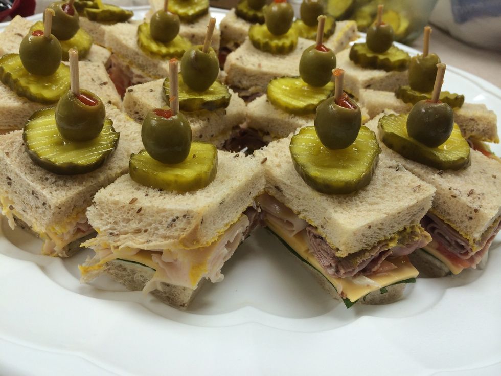 Place two pieces of bread together, cut off the edge of crusts and quarter. Place sandwich puck in to secure sandwich and put pickle and olive on top for a garnish. Enjoy!
