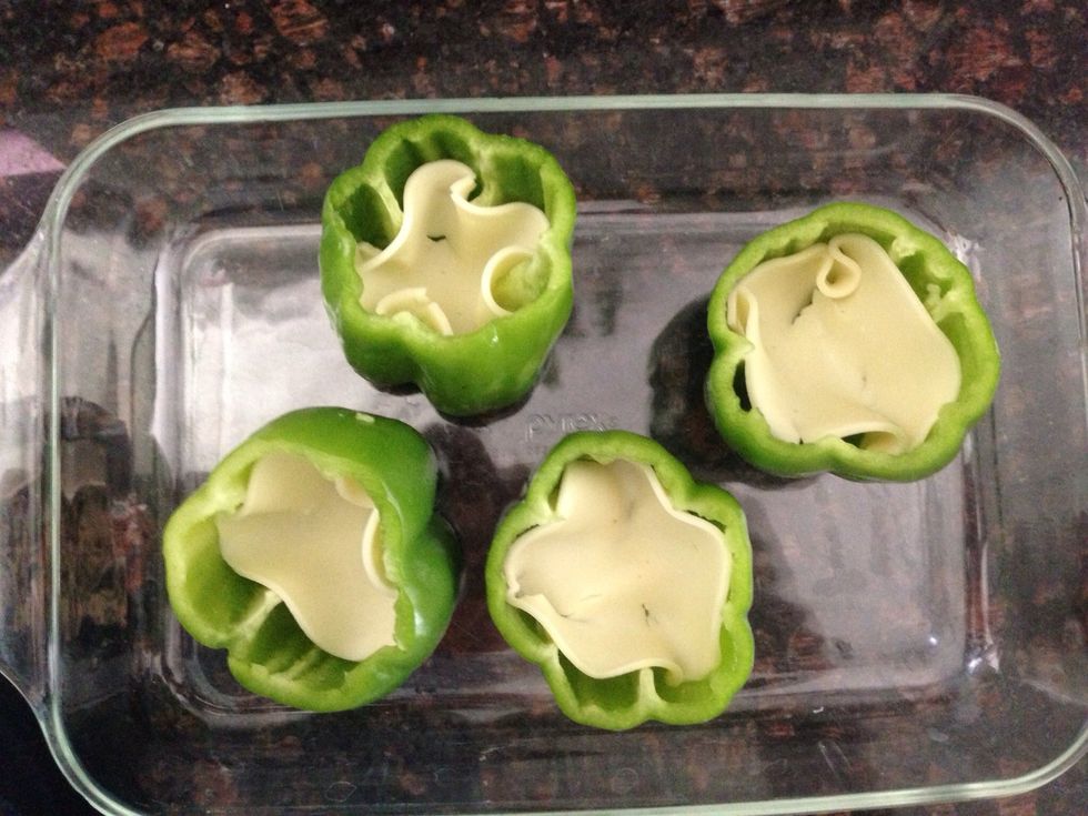 Place you peppers into a baking dish. Fill each pepper with 1 slice of provolone cheese.