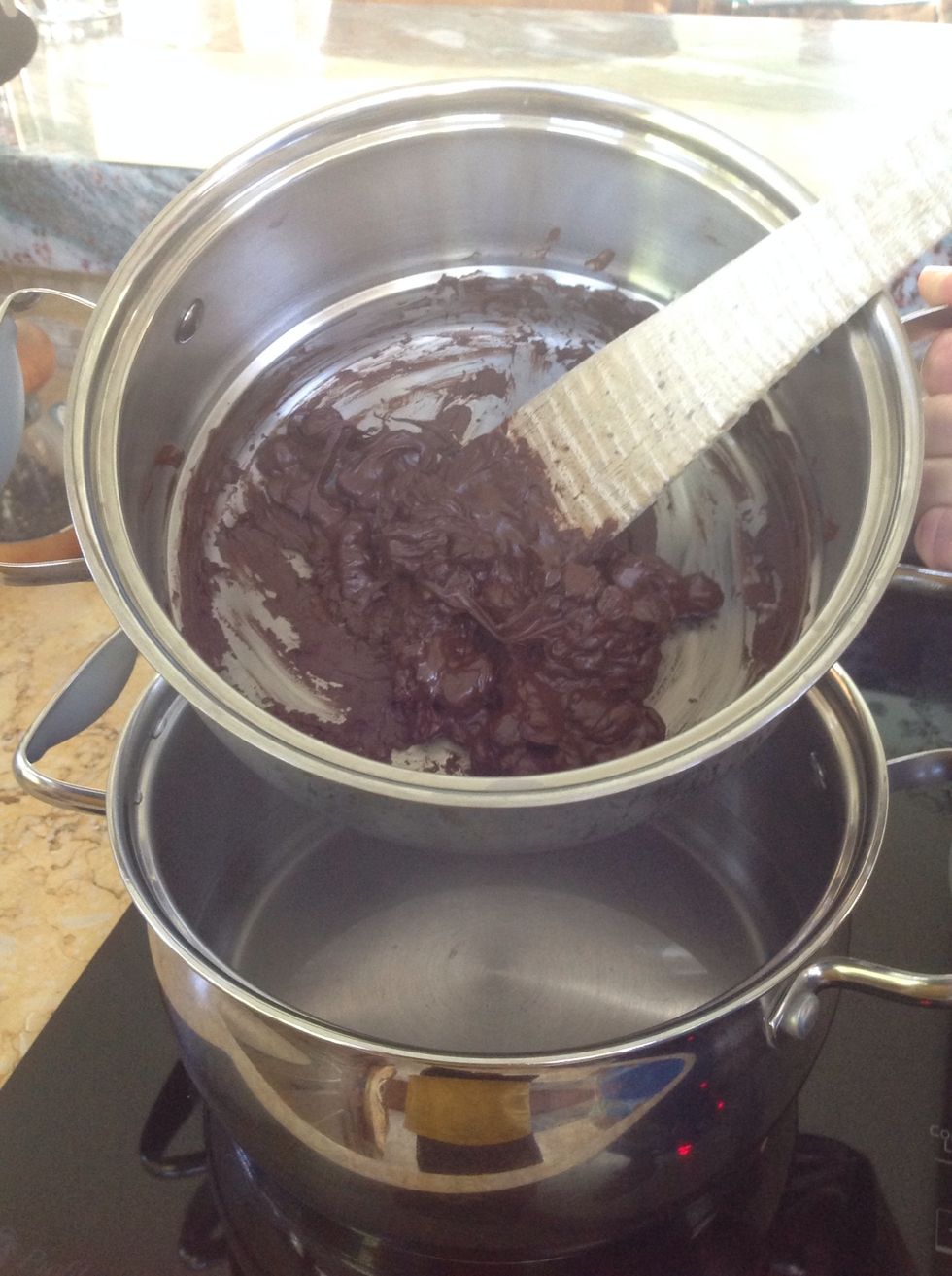 Place your chocolate in the top pan of a double boiler, over an inch of simmering water. Heat, stirring often, until the chocolate melts, without burning it. Remove from the water to let it cool.