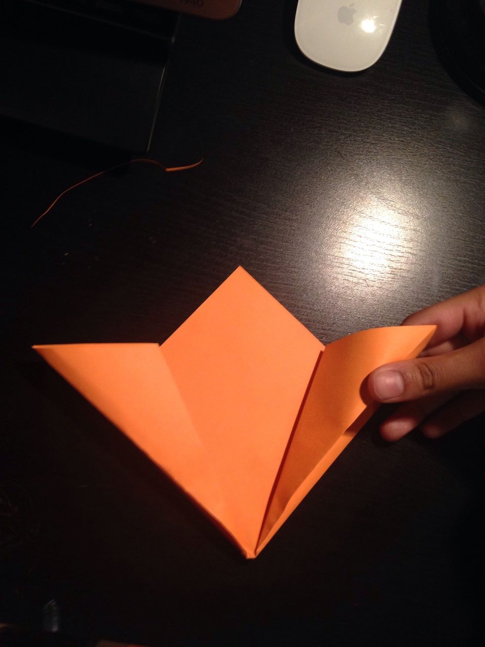 Place your finger in one of the outer pockets, and make a squash fold as shown in the next steps.