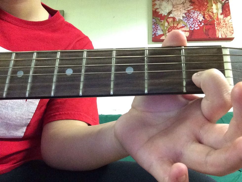 Place your first finger on the B string on the first fret. Frets are the sections from the pegs, down to the hole.