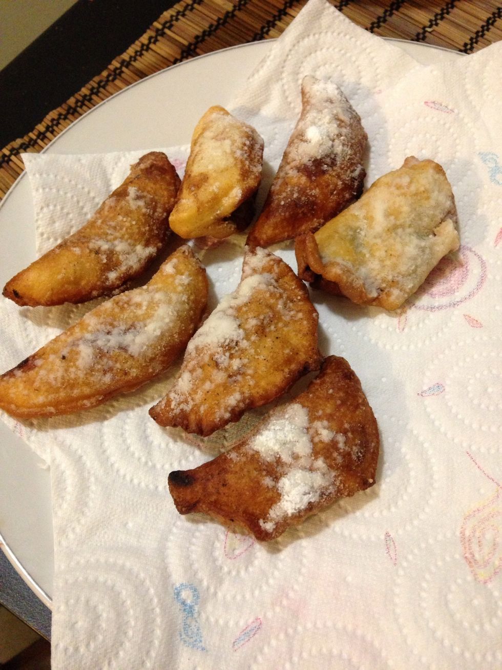 Place your fried empanadas on some kitchen roll in order to absorb the oil. Now add some icing sugar on top !