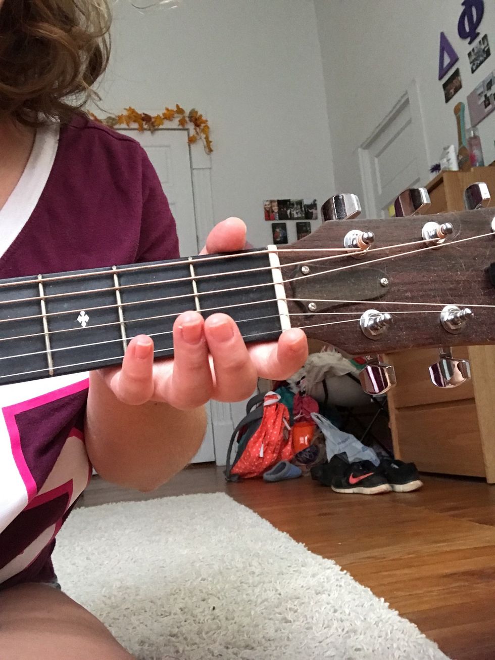 Place your left hand under the neck of the guitar on the first and second fret.