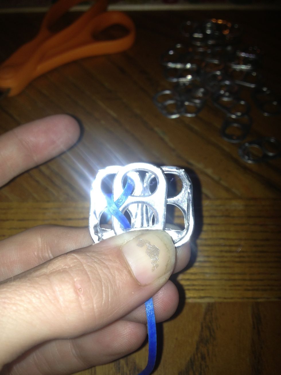 Place your next soda tab(rough side up) and put it under the last soda tab.