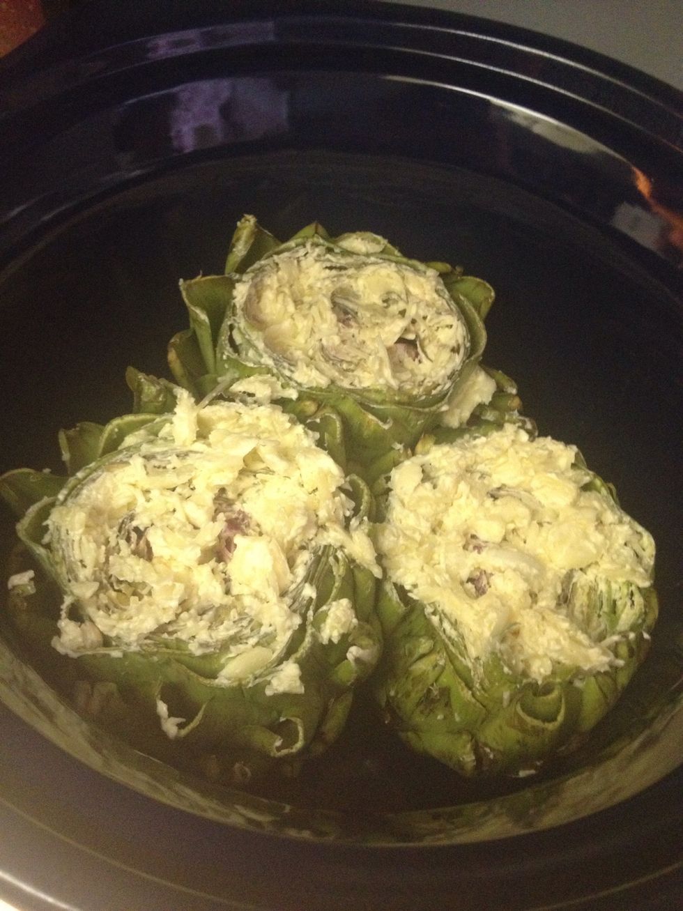 Place your prepared artichokes into a crock pot.