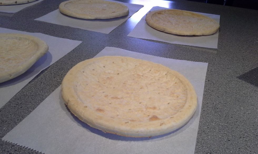 Place your prepared pizza crust onto parchment paper. The thicker the crust the better for freezing.