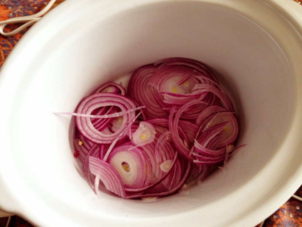 Place your sliced onions in the bottom of a slow cooker.