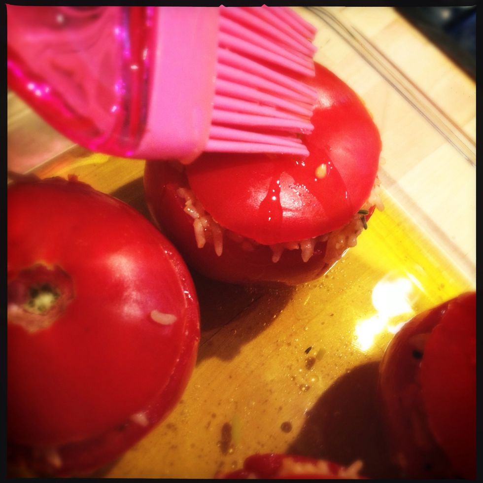 Place your stuffed tomatoes in the dish. Place back the cut off caps and grease the tomatoes with the mixture they are standing in. This will prevent them from burning in the oven.