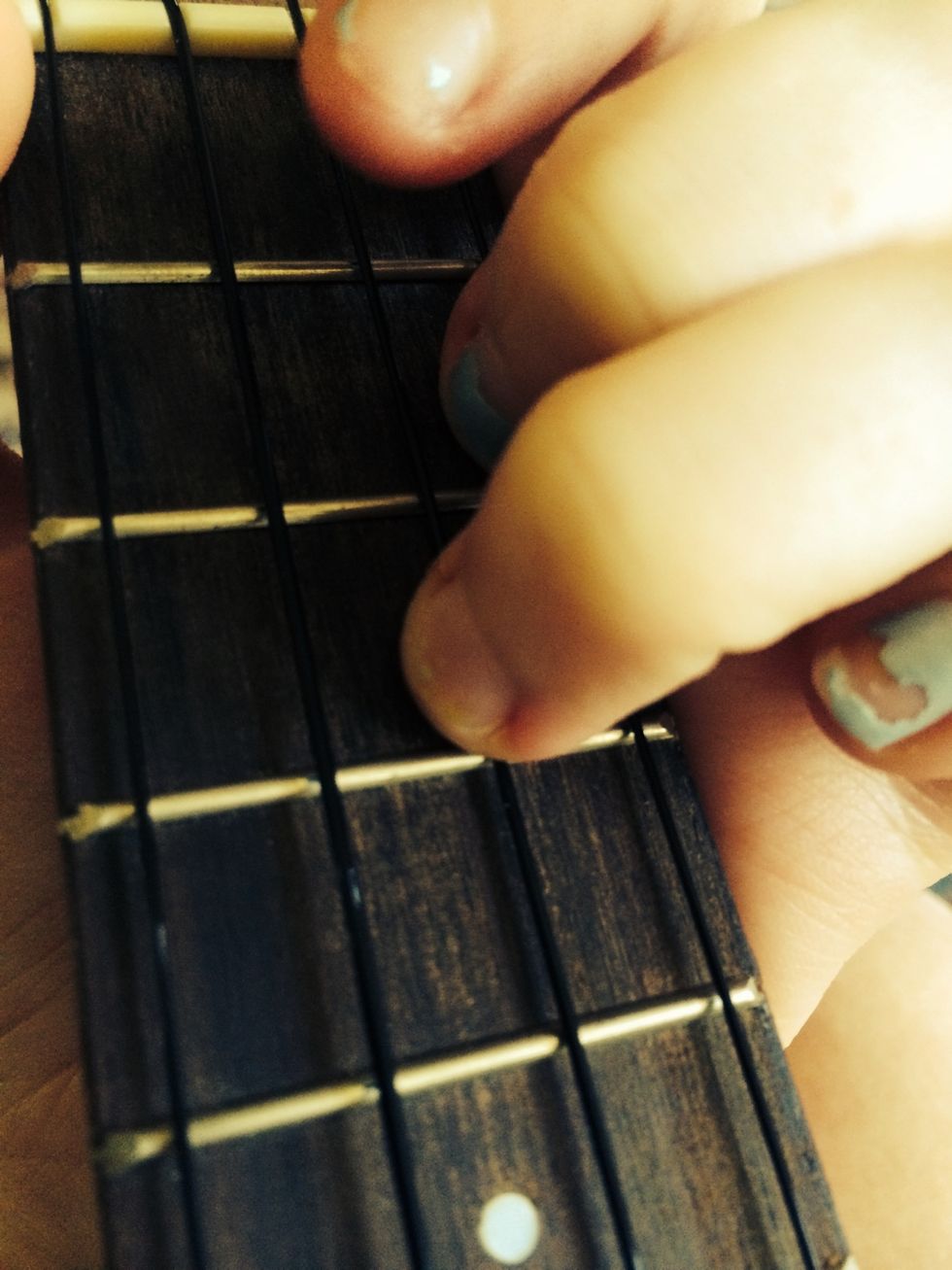 Place your third finger on the third fret of the E string.