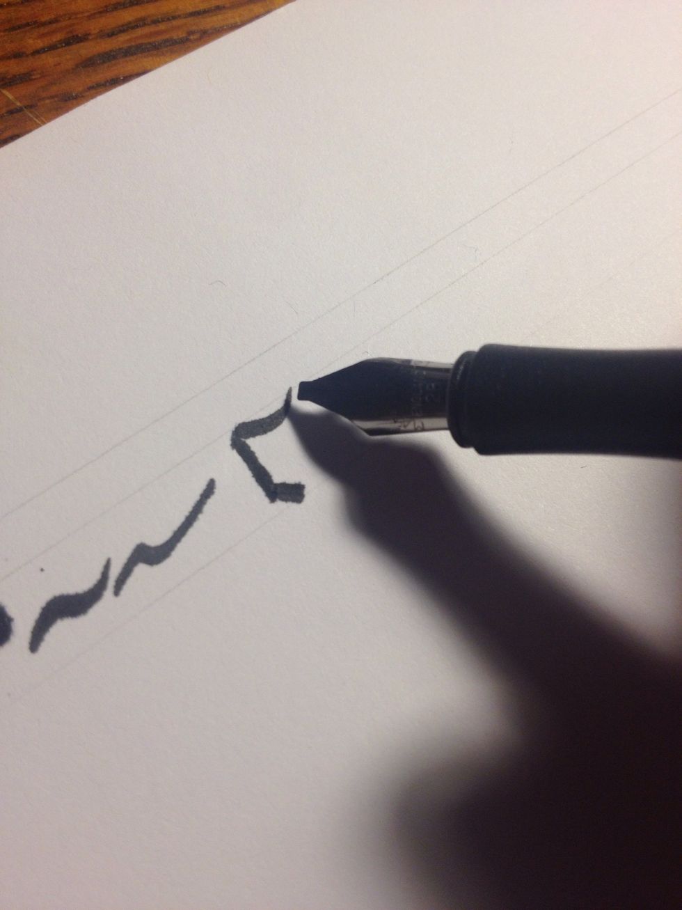Placing the top of your nib flush with the beginning of the first stoke, make a curved, boat-shaped stroke until you hit that top line again. It should start out thick and end thin.